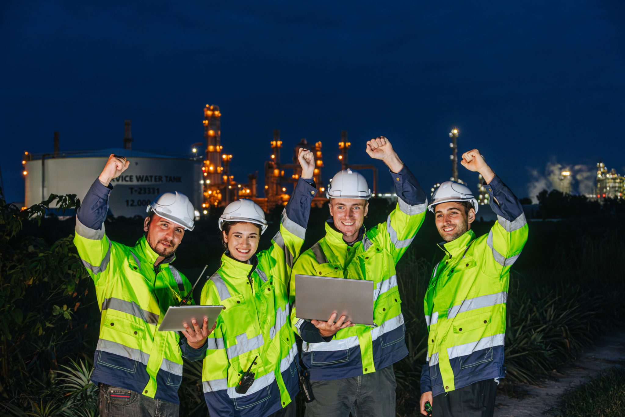 Four workers celebrating at industrial site.